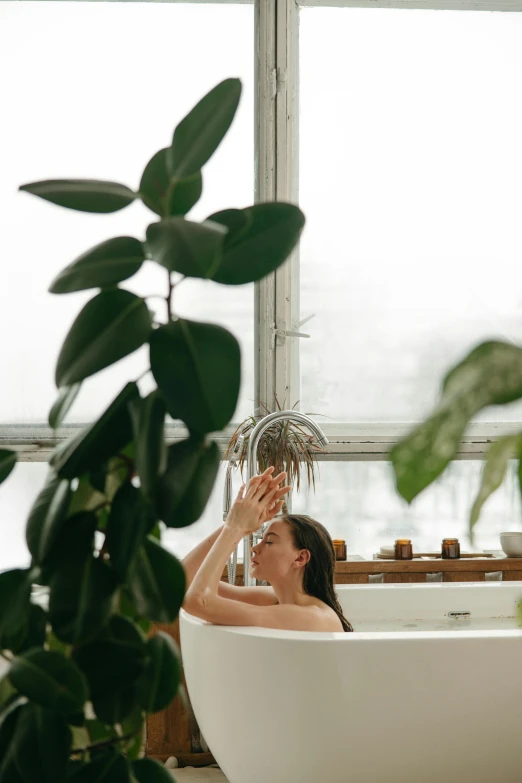 a woman sitting in a bath tub surrounded by greenery