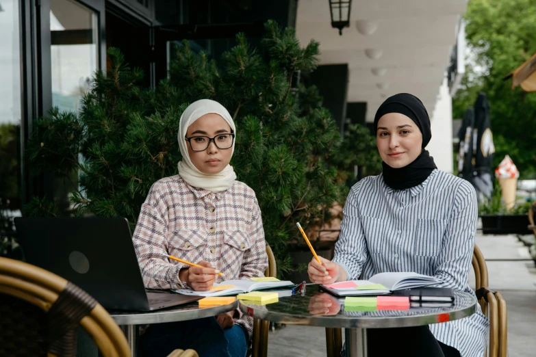 a woman sitting in front of a table next to a person