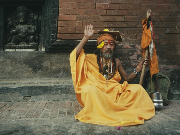 a man with beards and wearing a yellow dress sitting down