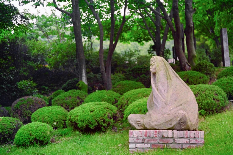 this is a small stone figure sitting in the middle of green bushes