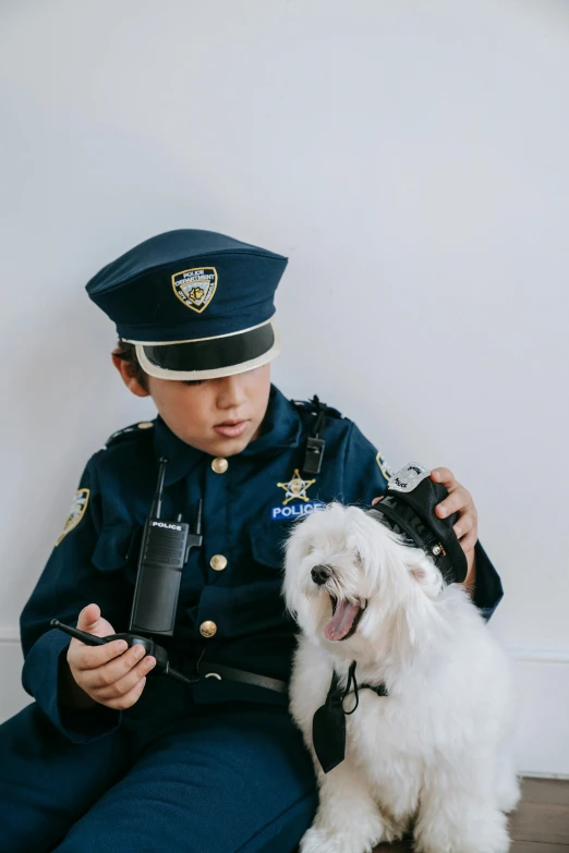 a  in a police uniform is playing with his small dog