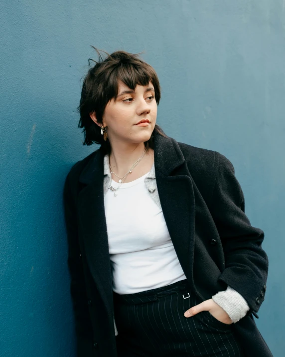 a woman leaning against the side of a blue wall