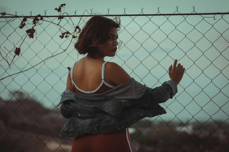 a woman is seen standing by a chain link fence