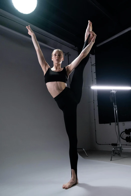 a young woman stretching in a room with a light on the floor