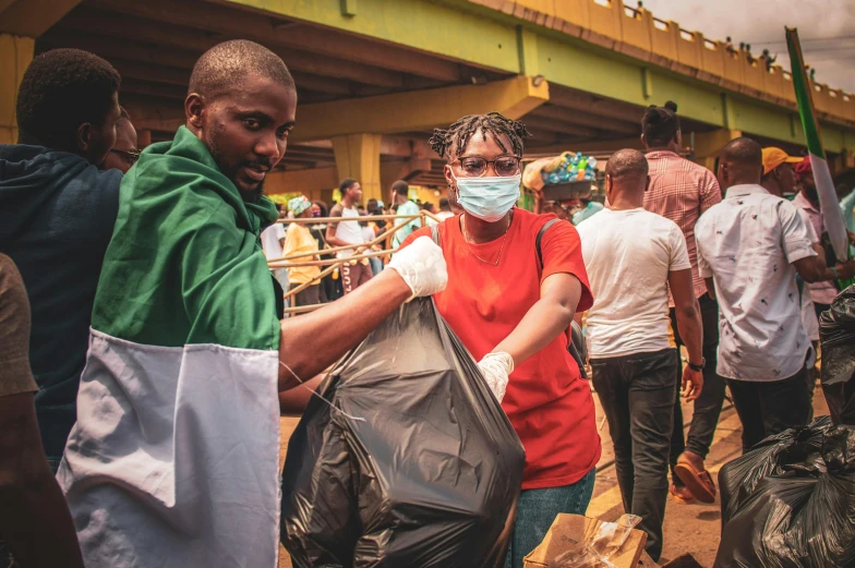 a man and woman are putting bags into their trash cans