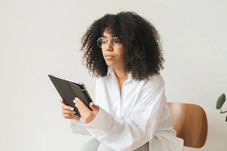 a young black woman is holding a tablet