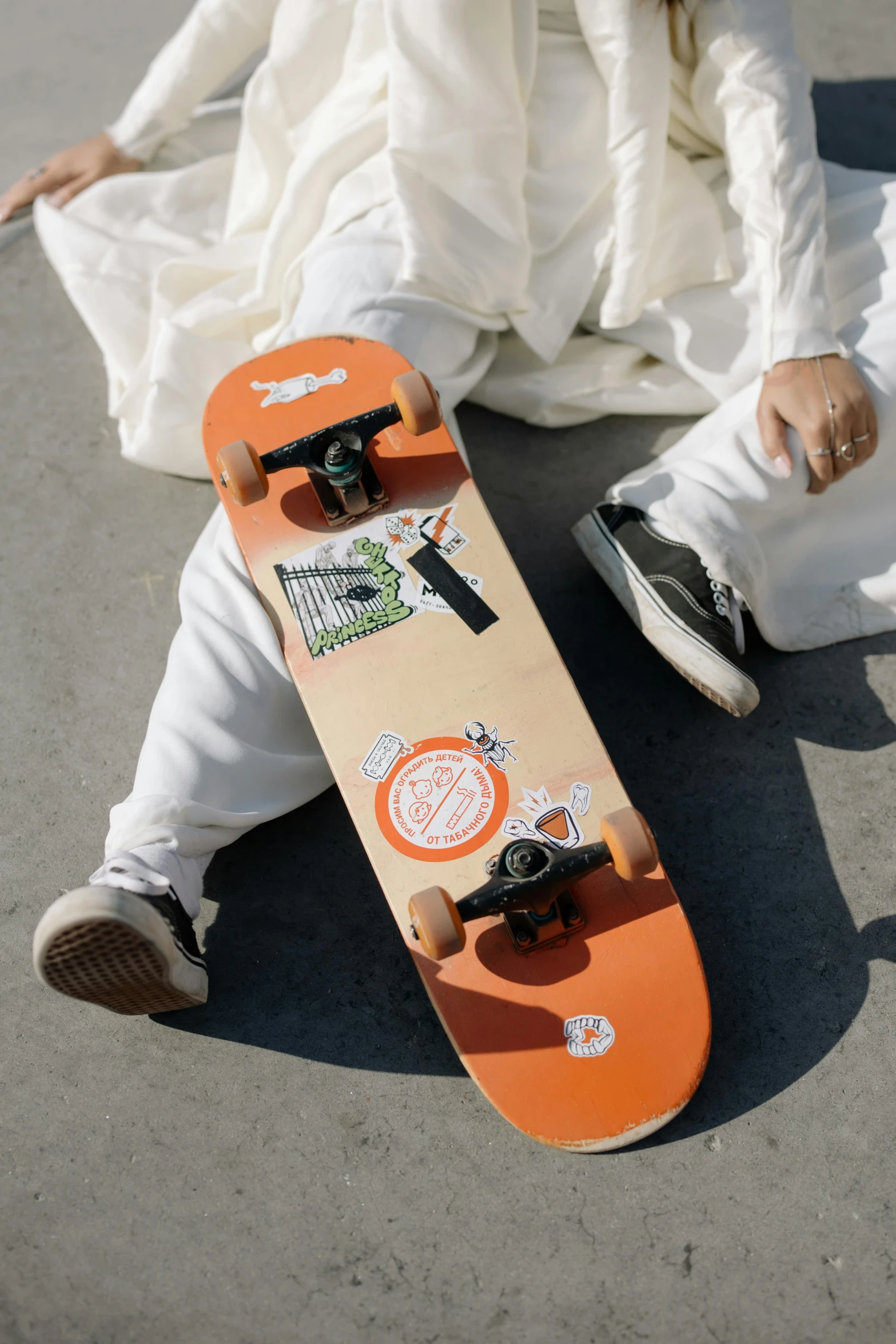 a person sits with a skateboard on a concrete surface