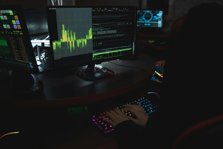 person with computer keyboard and monitor in dark room