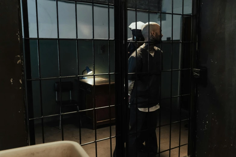 a man is standing behind a wire fence