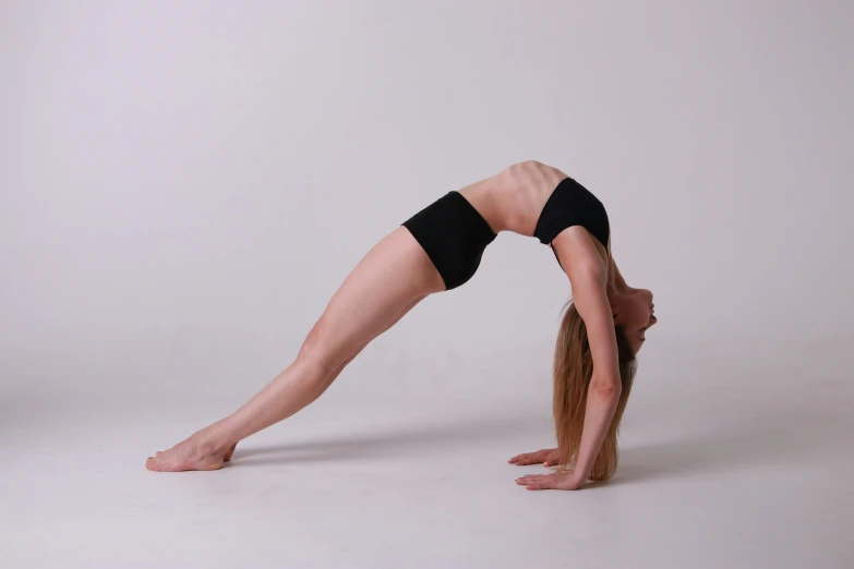 woman doing a yoga upward bend with her arms and legs bent over her head