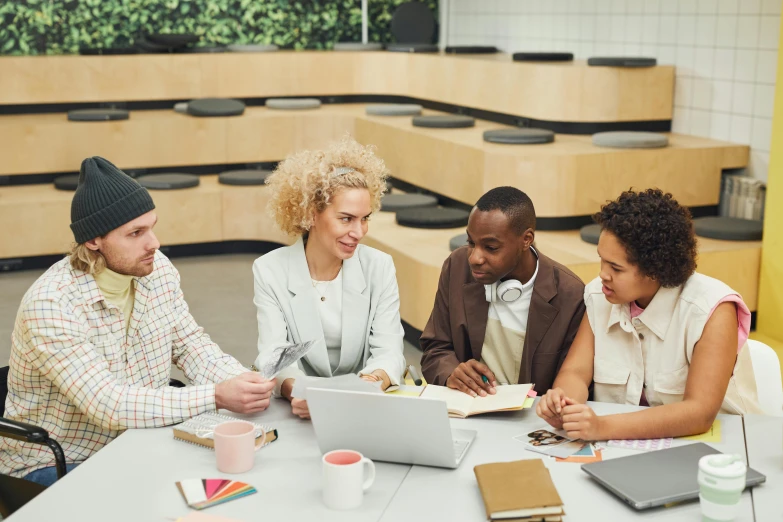 three people sitting at a table with an open book