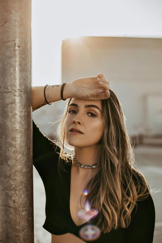 young woman with long hair wearing choker looking over wall