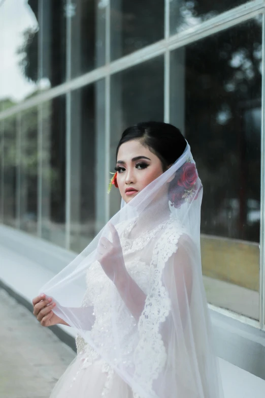 the woman in the wedding dress is standing near a window