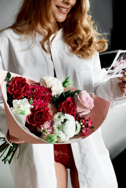 a woman holding a bouquet of flowers and a note