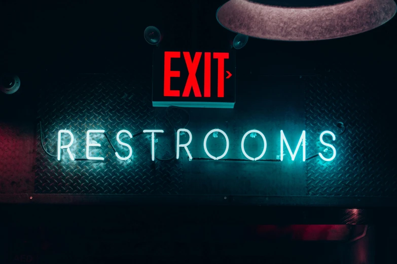 an exit and restroom neon sign with red letters