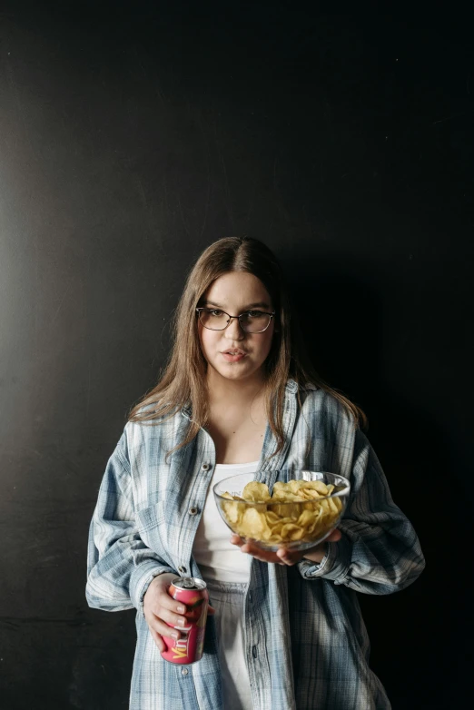 a woman in a plaid jacket holding a bowl full of fries