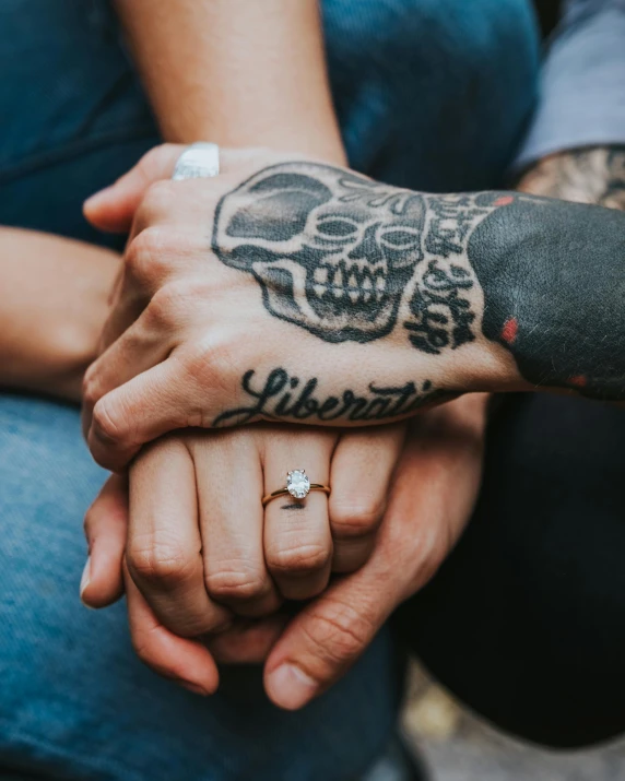 two people holding hands with tattoos on them