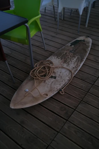a brown surfboard sitting on top of a wooden deck
