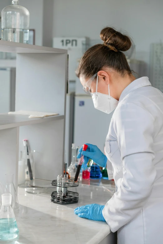 a scientist wearing a mask and gloves is doing a experiment