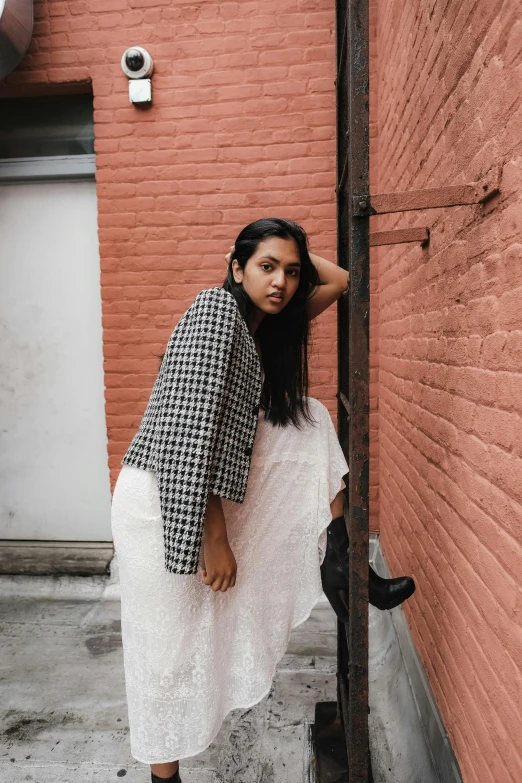 a woman leaning against a brick wall posing for a po