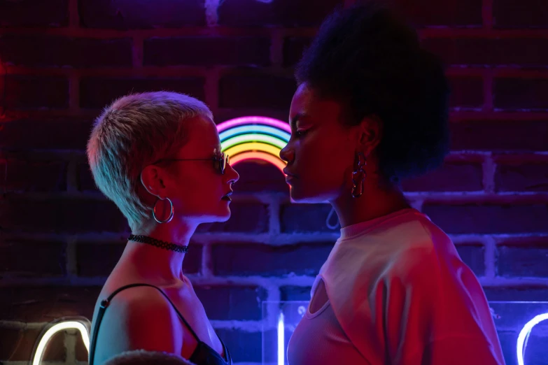 two woman are kissing in a room with lights on