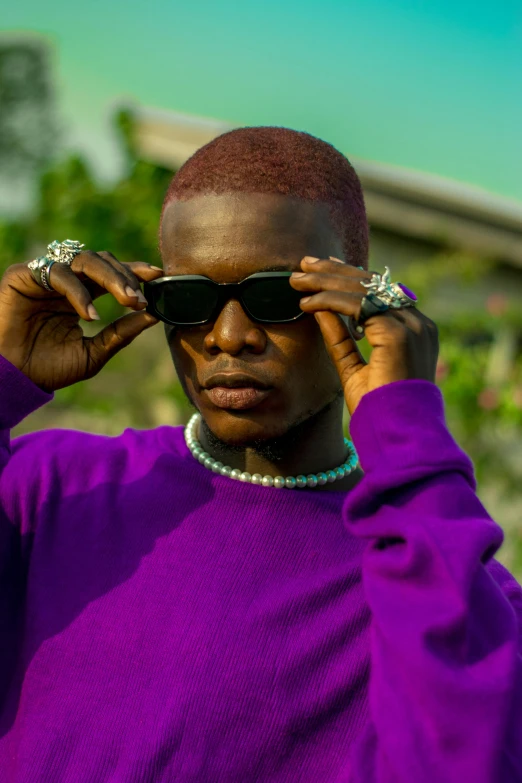 an african american woman in purple wears sunglasses and beads