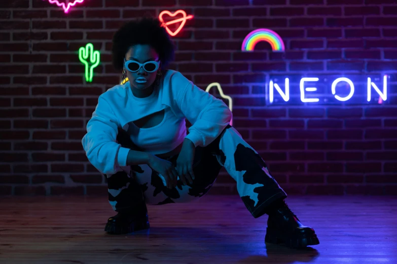 a person sitting down with a neon sign in the background