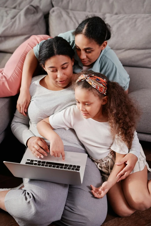 two girls sitting on the floor playing on a laptop