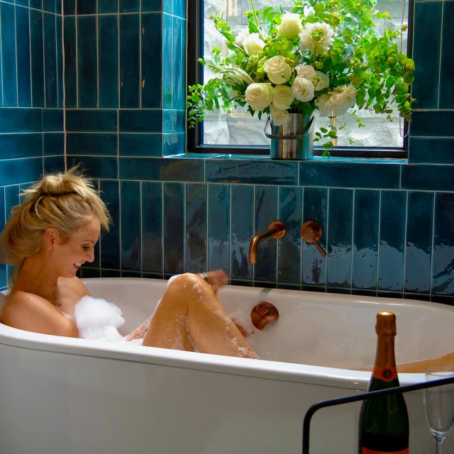 a woman sitting in a bath tub with bubbles and soap