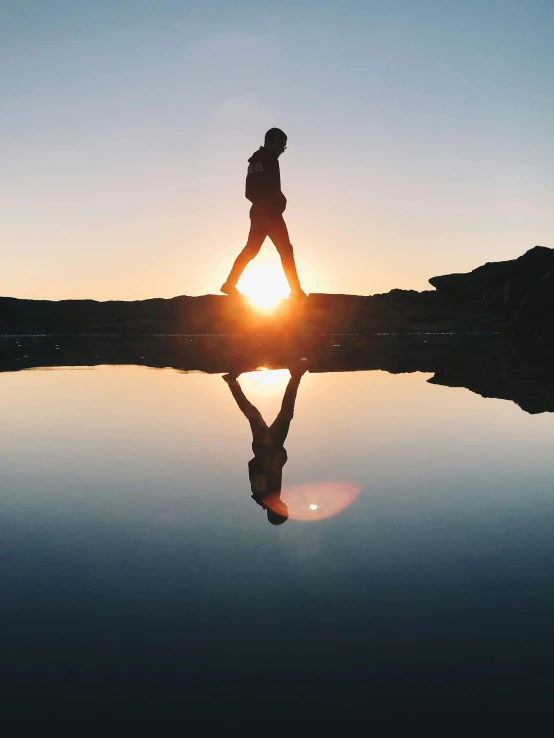 a person stands on a rock overlooking the water's edge