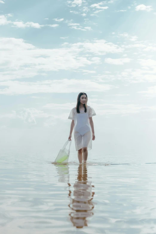 a woman walks through the water carrying her items