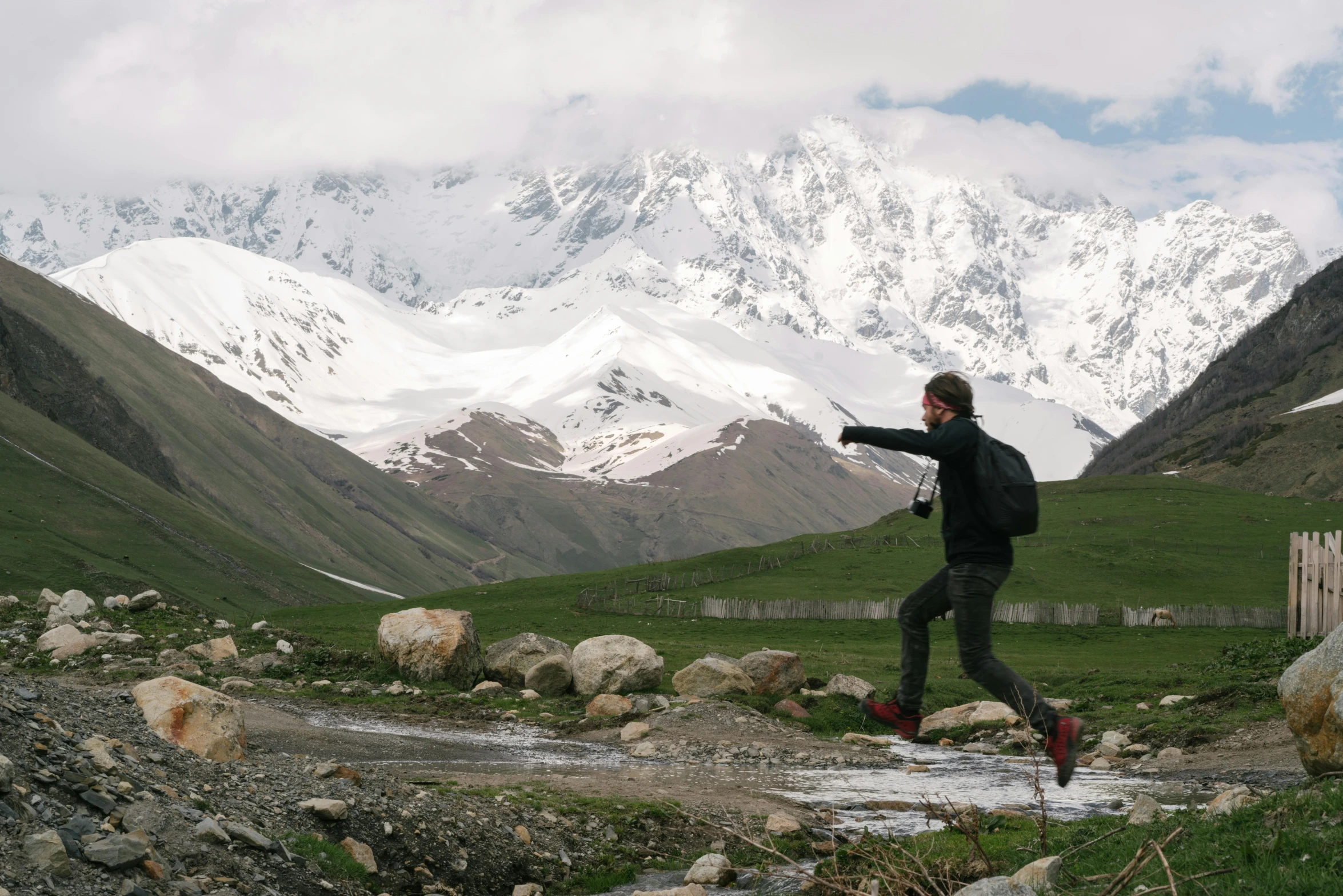 a man running on the rocky trail with mountains in the background