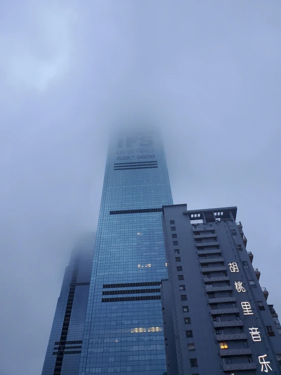 a tall skyscr in the clouds with some chinese characters on it