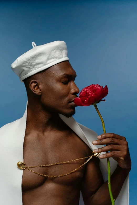 a man wearing a hat and holding a rose