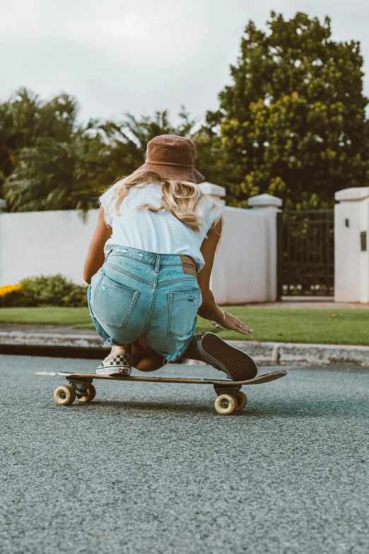 a girl in jeans doing skateboard tricks on the road