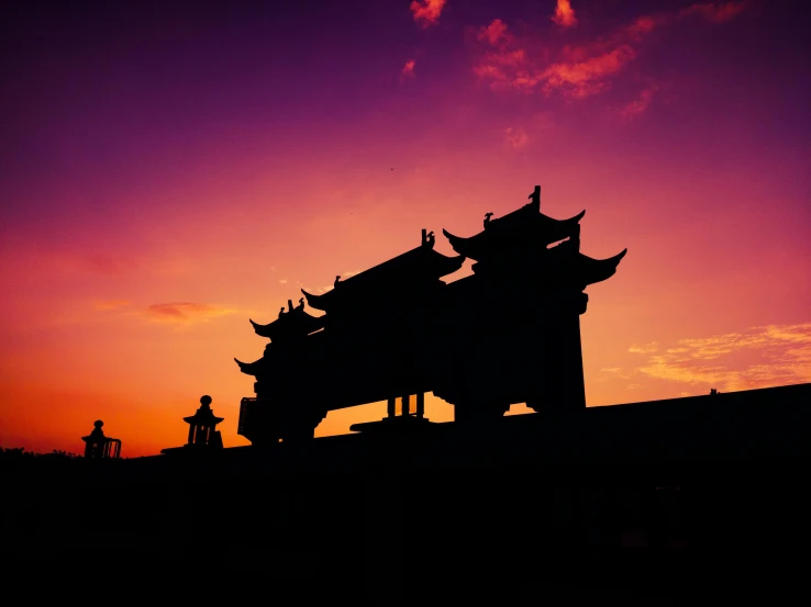 a silhouetted image of a small building against a purple sunset