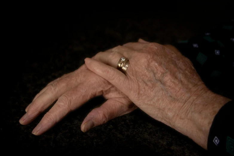 the person is holding a gold wedding band