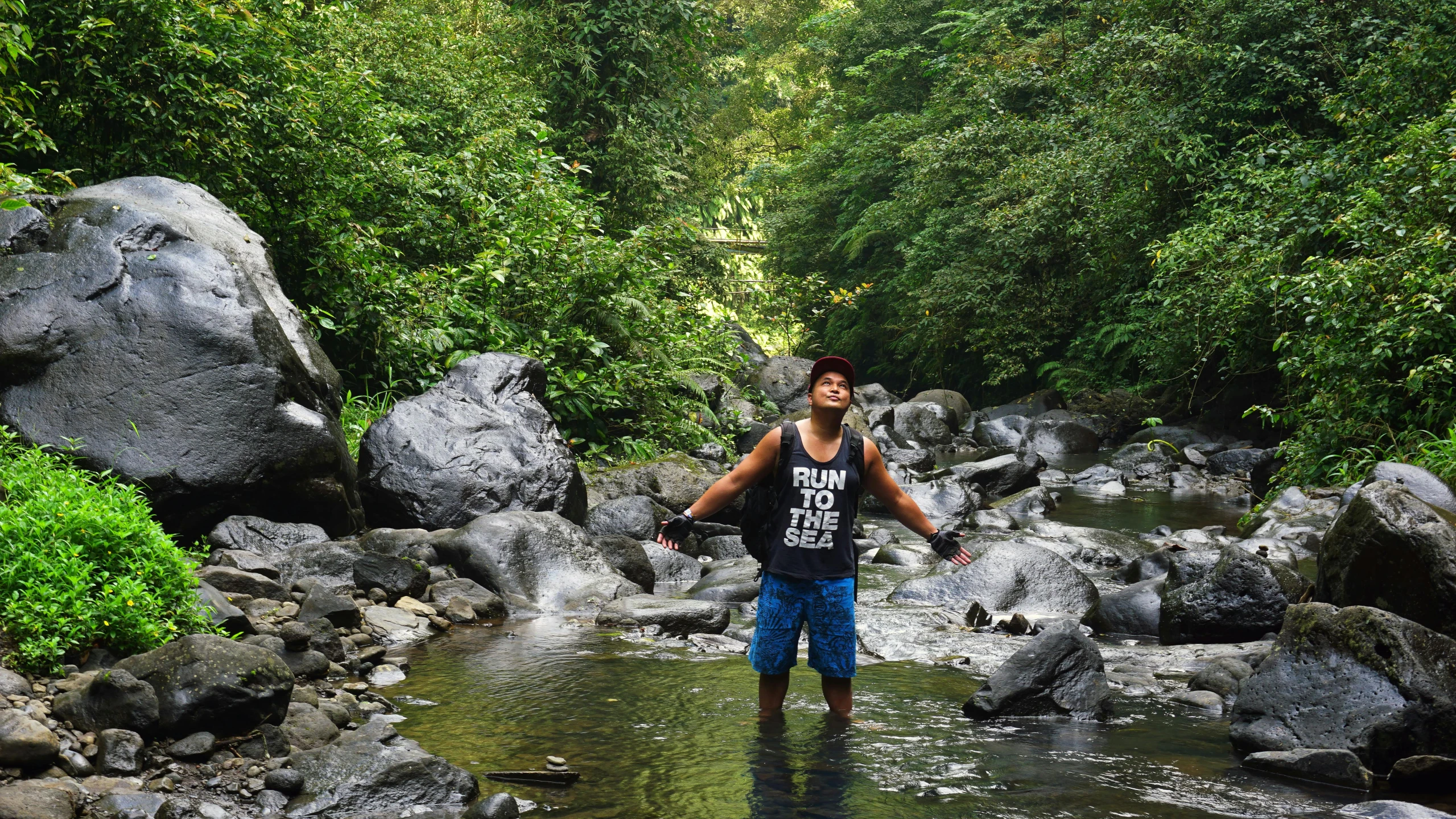 a person walking through a small river holding on to a rope