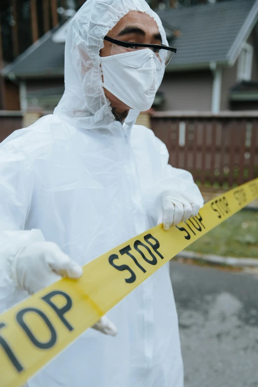 a man wearing all white and holding a yellow tape around his neck