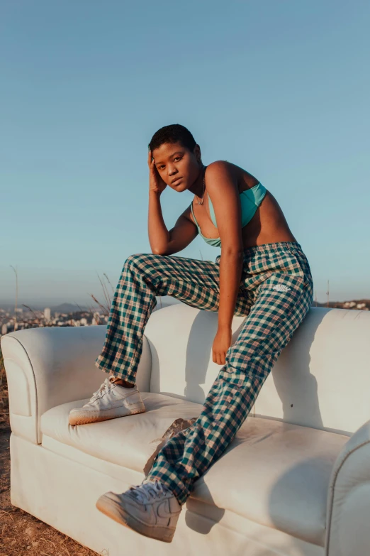 a woman is sitting on the back of a couch in checkered pants