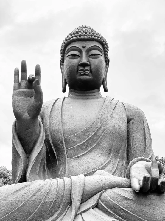 buddha statue showing open hand with grey sky background