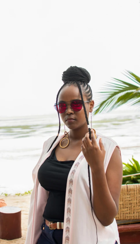 a woman in sunglasses and shawl standing on the beach