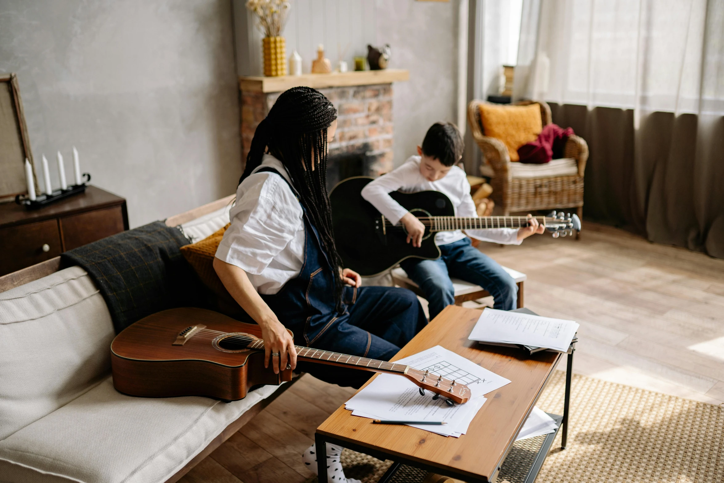 two people with guitars sit on couches in a room