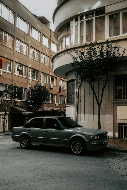 a dark colored compact station wagon sits near a building in the city