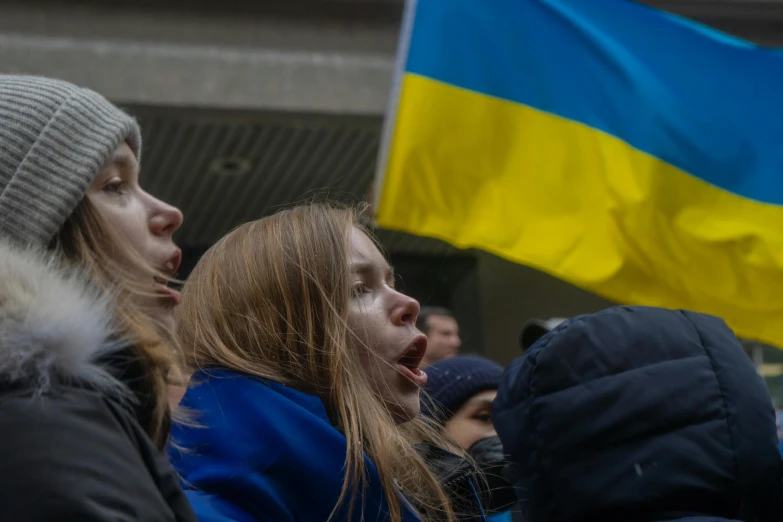 people at a protest, one holding the national flag of ukraine