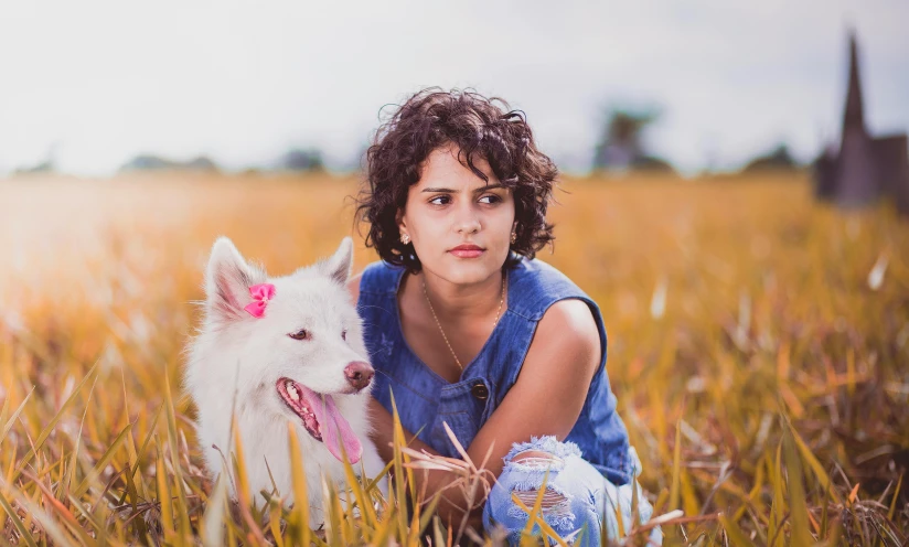 a boy is posing with a dog in a field