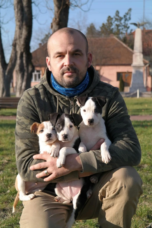 a man is holding three puppies in his hands