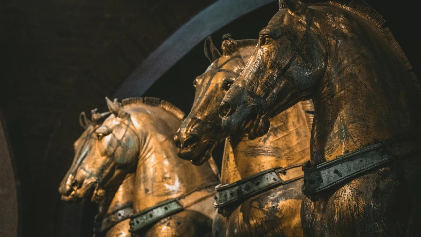 golden horses stand together on the top of a tower