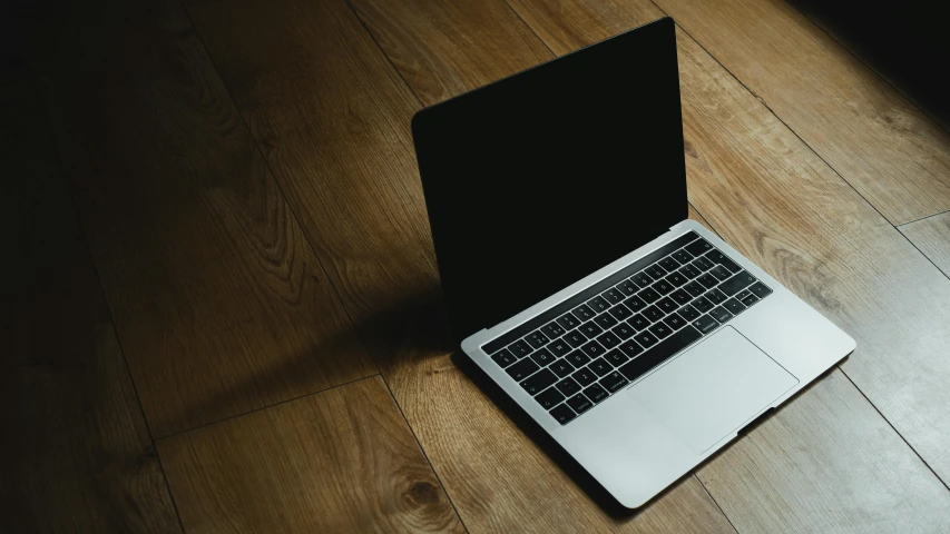 an open laptop sitting on top of a wooden floor