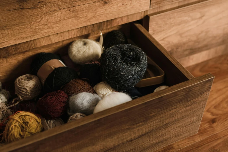 yarn, needles and balls in a wooden box on a floor